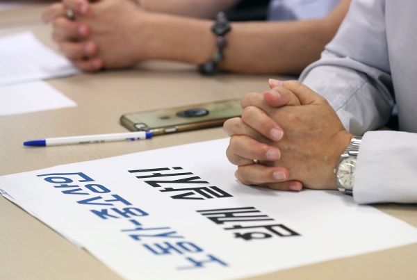 지난 23일 오후 서울 영등포구 한국중소상인자영업자총연합회 사무실에서 열린 최저임금 인상 입장 발표 기자회견에서 한 참석자가 손팻말 위에 손을 모으고 있다. (사진=연합뉴스)