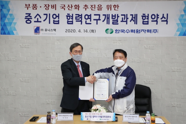 정재훈 한수원 사장(왼쪽)과 정윤걸 유니스텍 대표이사가 '격납건물 내부 철골 내진간극 측정용 장비 국산화 개발'을 위한 협약을 체결하고 기념 촬영을 하고 있다.(사진=한수원)