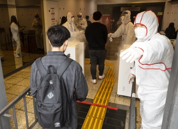 지난 24일 오전 서울 성북구 서경대학교에서 열린 SK 그룹 상반기 공채 SKCT(인적성 시험)에서 방호복을 입은 관계자가 응시생들의 입실을 안내하고 있다. (사진=연합뉴스)