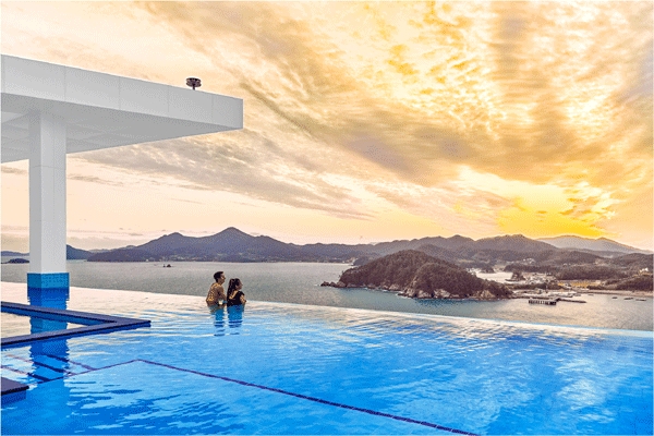 한화리조트 거제 벨버디어의 인피니티풀 안에서 남해바다를 보는 신혼부부 이미지. (사진=한화호텔앤드리조트)