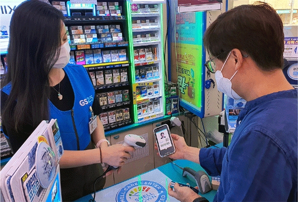 지에스(GS)리테일 임직원(오른쪽)이 편의점 GS25에서 담배를 살 때 모바일 운전면허증으로 성인 여부를 확인해보고 있다. (사진=지에스리테일)