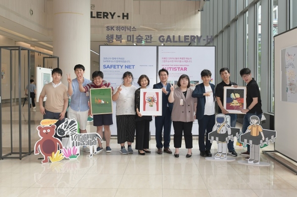 기념식에 참석한 SK하이닉스 관계자와 오티스타 소속 자폐인 디자이너들이 사진을 찍고 있다. 사진 왼쪽 다섯 번째부터 오티스타 이소현 대표, SK하이닉스 이일우 EE담당 (사진=SK하이닉스)