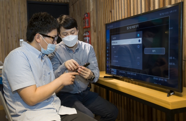 삼성전자 상품전략팀 직원(사진 오른쪽)이 서울 관악구에 위치한 실로암 시각장애인 복지관에서 한 시각장애인에게 삼성전자 스마트TV의 접근성 기능에 대해 설명하고 있다. (사진=삼성전자)