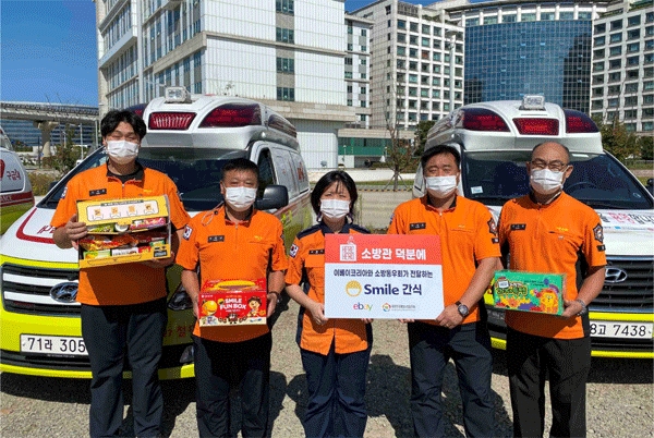 지난 24일 인천 중구 운서동 인천국제공항에서 중앙검역센터 이송지원단 소방관들이 이베이코리아로부터 건네받은 스마일 간식을 들어보이고 있다. (사진=이베이코리아) 