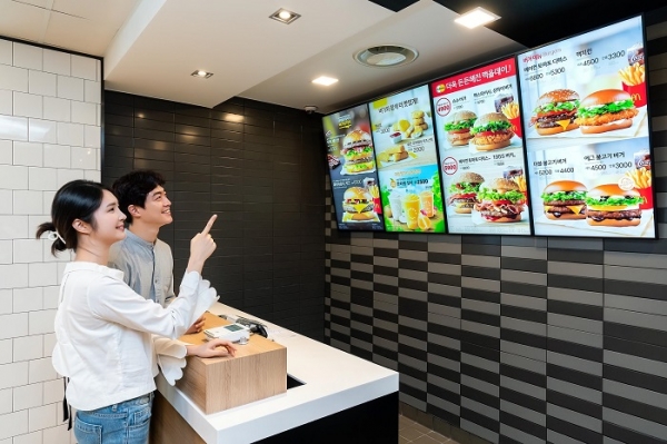삼성전자 모델이 경기도 고양시에 위치한 맥도날드 고양삼송DT점에 설치된 삼성 스마트 사이니지를 소개하고 있다. (사진=삼성전자)