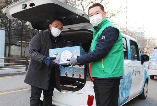 김인규 하이트진로 대표가 2일 서울 서초구 하이트진로 서초동 사옥 앞에서 강현구 곰달래어르신복지센터 사회복지사에게 떡국 재료를 건네고 있다. (사진=하이트진로)