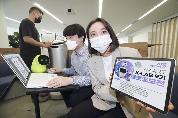 KT 직원들이 로봇 우수기업 선발 공모전 포스터를 확인하고 있다. (사진=KT)