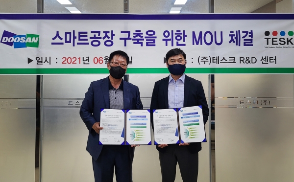이용진 두산인프라코어 구매총괄 전무(오른쪽)와 황정상 ㈜테스크 대표가 스마트공장 구축 지원 양해각서를 체결하고 있다. (사진=두산인프라코어)