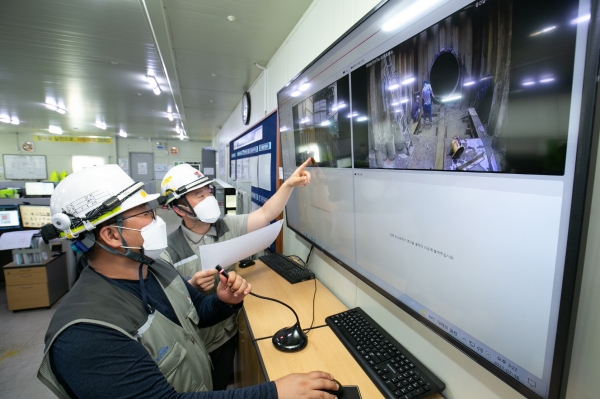 액셤캠과 위치태그 등이 장착된 스마트 안전모를 착용하고 스마트폰으로 현장을 확인하는 작업자의 모습. (사진=쌍용건설)