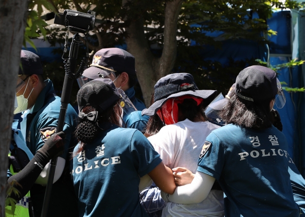 23일 강원 원주시 국민건강보험공단 인근에서 열린 고객센터 노조 직접 고용 촉구 결의대회에서 집회 참가자가 통제선을 넘으려다 경찰에 제지당하고 있다. (사진=연합뉴스)