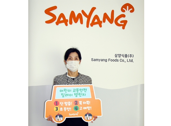 어린이 교통안전 릴레이 챌린지에 동참한 김정수 삼양식품 총괄사장이 '어린이 보호구역 1단 멈춤! 2쪽 저쪽! 3초 동안! 4고 예방!'이라고 적힌 표어를 들어 보이고 있다.  (사진=삼양식품)