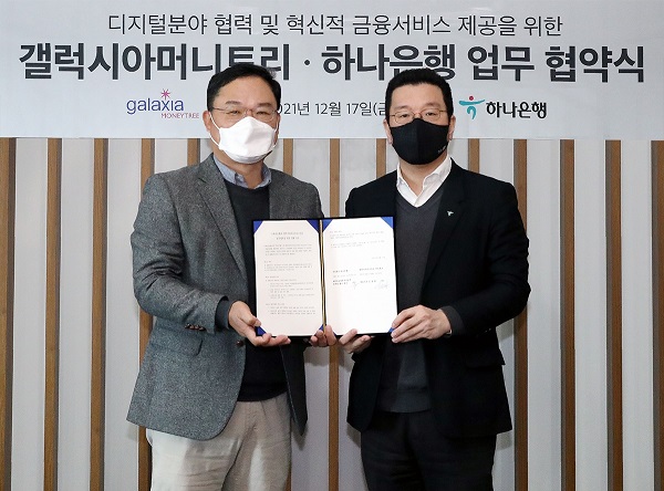 협약식에 참석한 황보현우 하나은행 데이터&제휴투자본부장(오른쪽)과 신동훈 갤럭시아머니트리 대표이사가 협약서를 들고 기념촬영을 하고 있다. (사진=하나은행)
