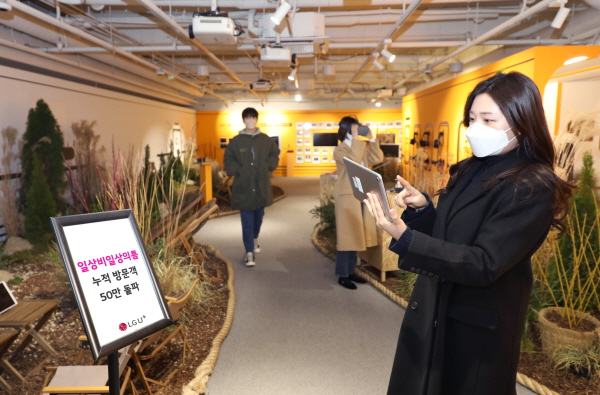 LG유플러스 모델이 '로컬트레인' 전시가 진행 중인 일상비일상의틈 지하 1층에서 누적 방문객 50만 돌파를 소개하는 모습. (사진=LG유플러스)