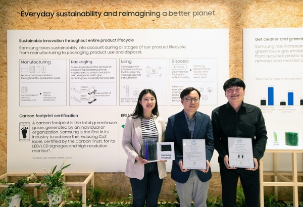 ISE 2022가 열리고 있는 스페인 바르셀로나 피라 그라 비아 전시장에서 삼성전자 영상디스플레이사업부 Enterprise 개발 이종포 상무(가운데)와 개발자들이 사이니지 제품 탄소 발자국 인증서와 제품에 활용되는 재생 플라스틱을 들고 있다. (사진=삼성전자)