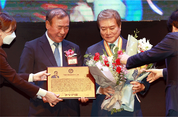 소진세 교촌에프앤비㈜ 회장(오른쪽)이 15일 서울 강남구 그랜드인터컨티넨탈 파르나스 호텔에서 열린 '2022 고대법대인의 밤' 행사에서 '자랑스러운 고대법대인상'과 꽃다발을 건네받고 있다. (사진=교촌에프앤비) 