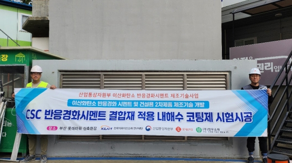 롯데건설 직원들이 부산 롯데타워 현장에서 이산화탄소 반응경화 시멘트를 활용한 코팅제를 시공하고 기념촬영을 하고 있다. (사진=롯데건설)