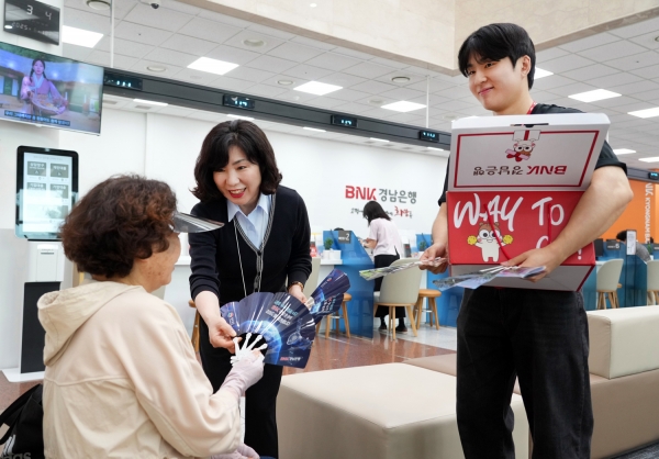 BNK경남은행 직원들이 영업점을 찾은 지역민들에게 부채를 나눠 주고 있다. (사진=BNK경남은행)