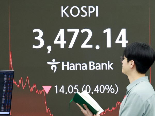 24일 서울 을지로 하나은행 본점 딜링룸에서 한 외환딜러가 증시 현황판 앞을 지나고 있다. (사진=연합뉴스)