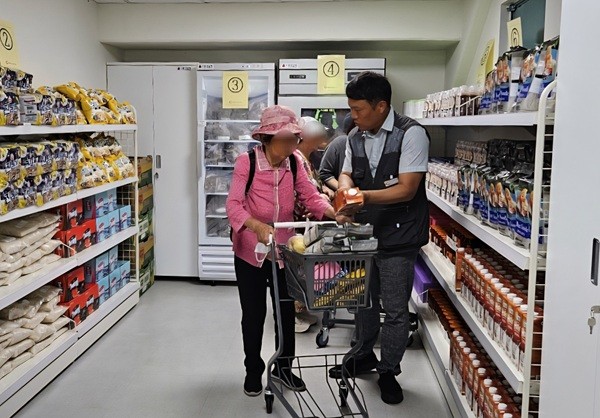 '그냥드림' 시범 사업장으로 선정된 광명푸드뱅크마켓센터에서 직원이 이용자가 식료품을 고르는 것을 돕고 있다. (사진=광명시)